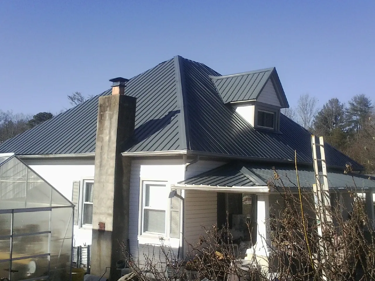 Dark blue standing seam metal roof on a white farmhouse with dormer — Slate & Tile Roof Repair by Roofing Brothers in Kalama