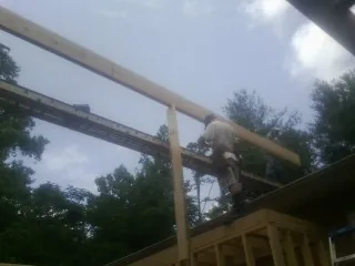 Carpenter setting a ridge beam over a new addition frame — Ice Dam Removal by Roofing Brothers in Kalama