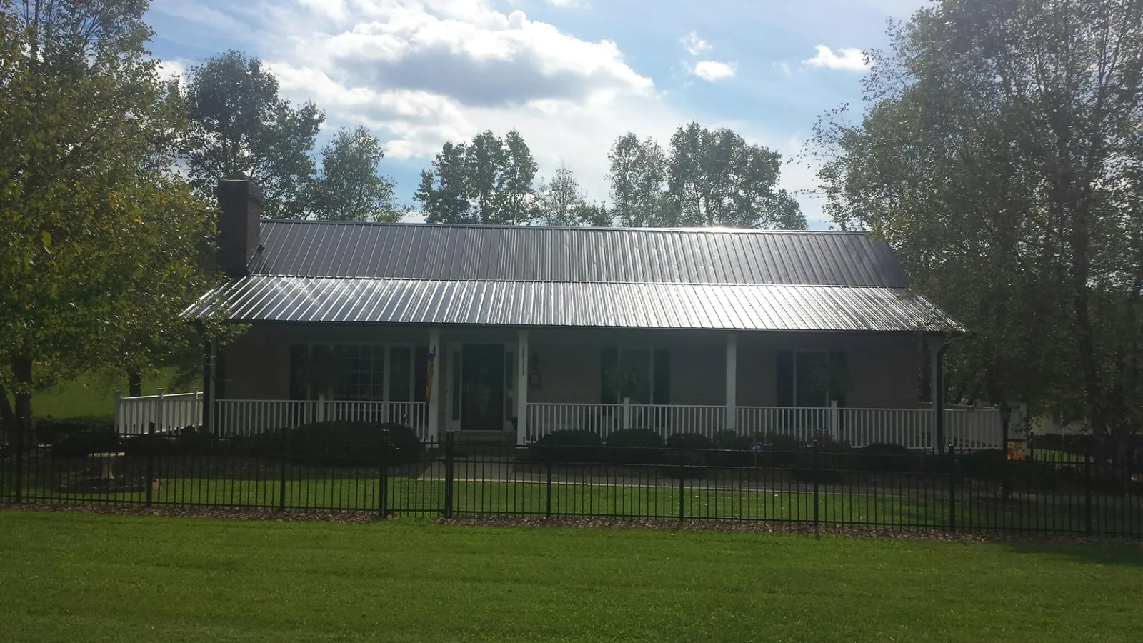Gray metal roof on a brick ranch with a full width front porch — Gutter Guard Installation work by our crew in Kalama