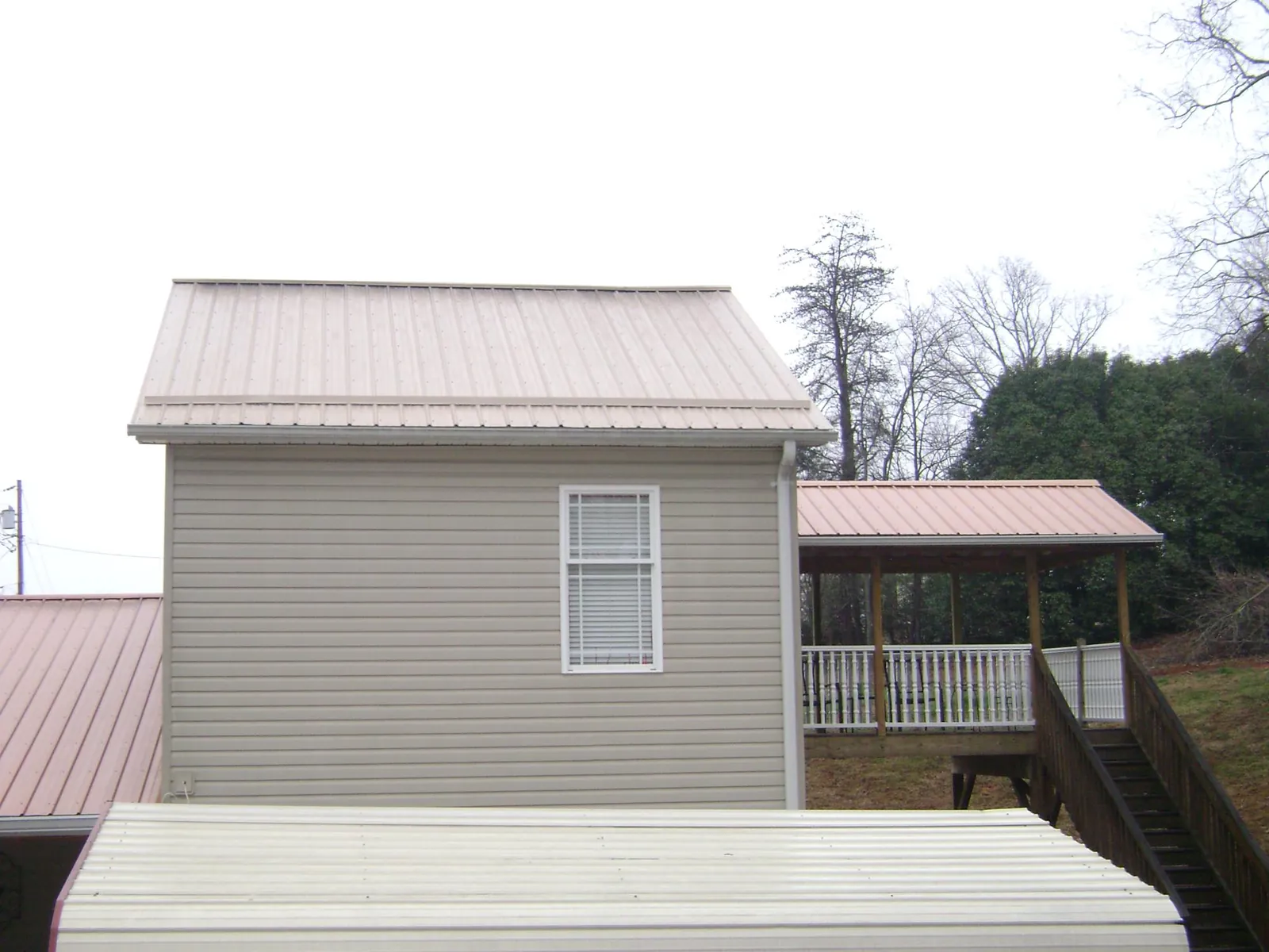 Tan metal roofs on a two story addition and attached porch, from a Roof Replacement job in Kalama