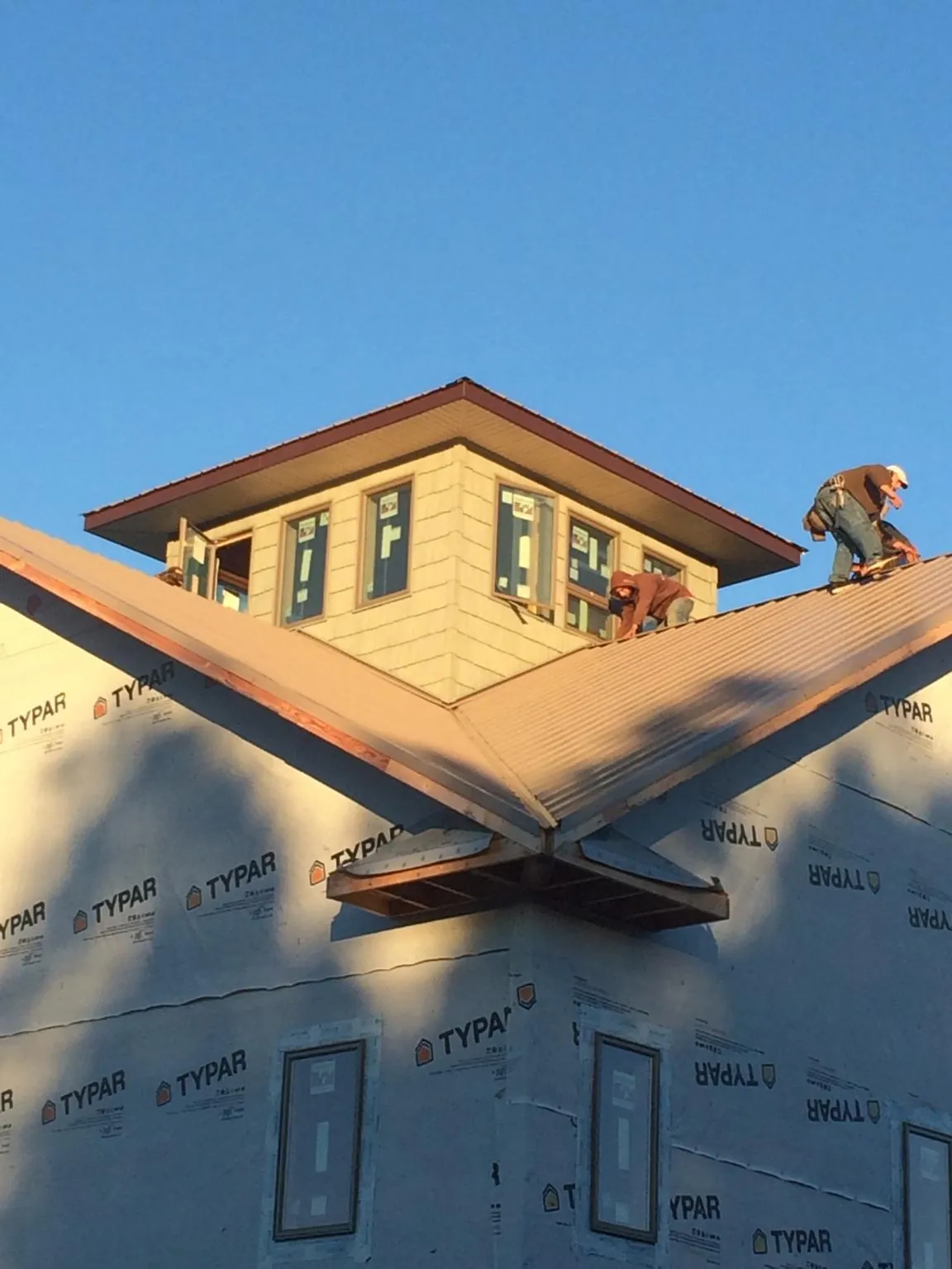 Roofers working around a rooftop cupola on a new metal roof at sunset — Roof Waterproofing in Kalama by Roofing Brothers